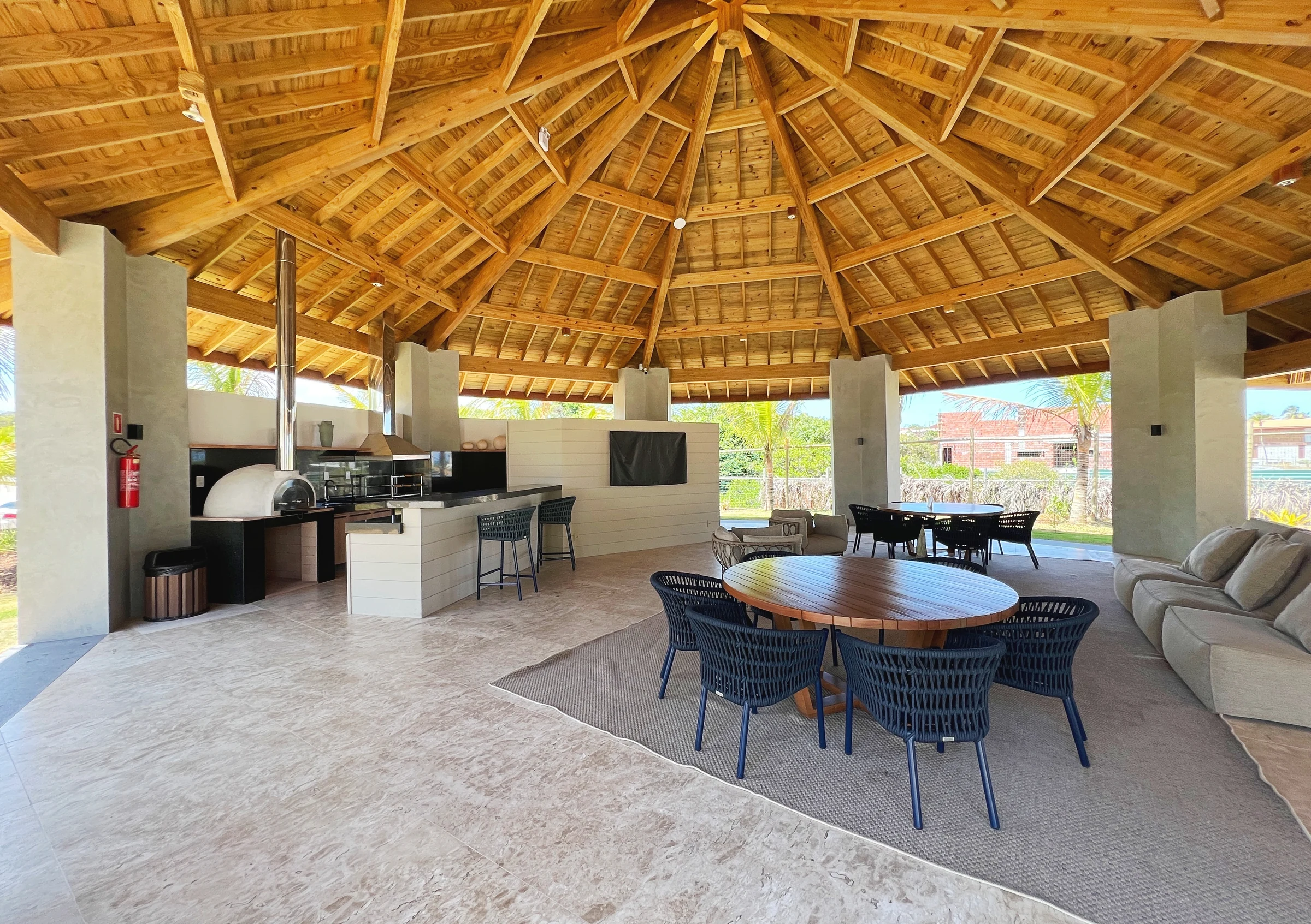 Pavilhão coberto com cozinha, mesa de jantar e área de estar.